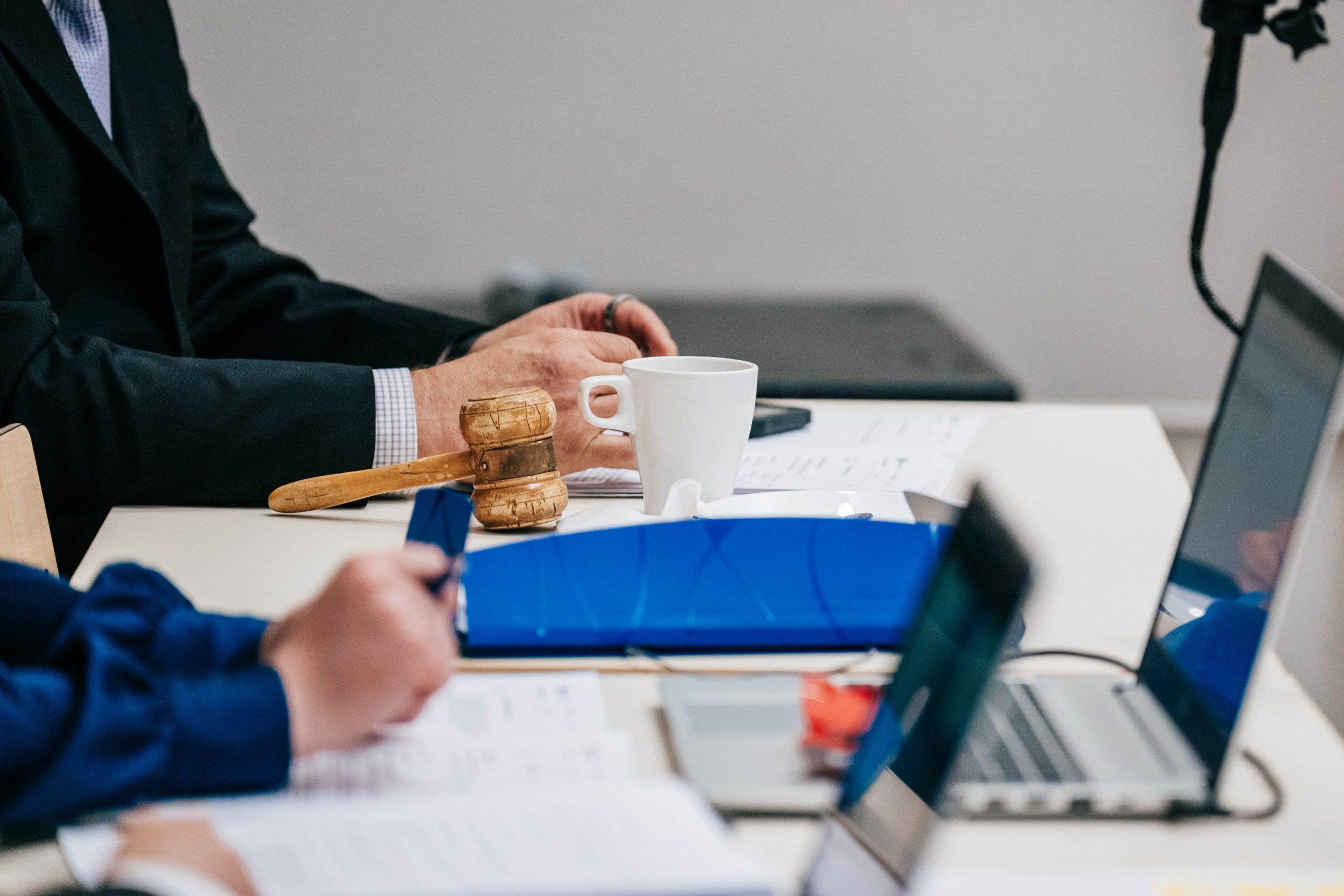 Kunnanvaltuuston kokouksessa puheenjohtajan nuija, tietokoneita ja kokouspapereita pöydällä.