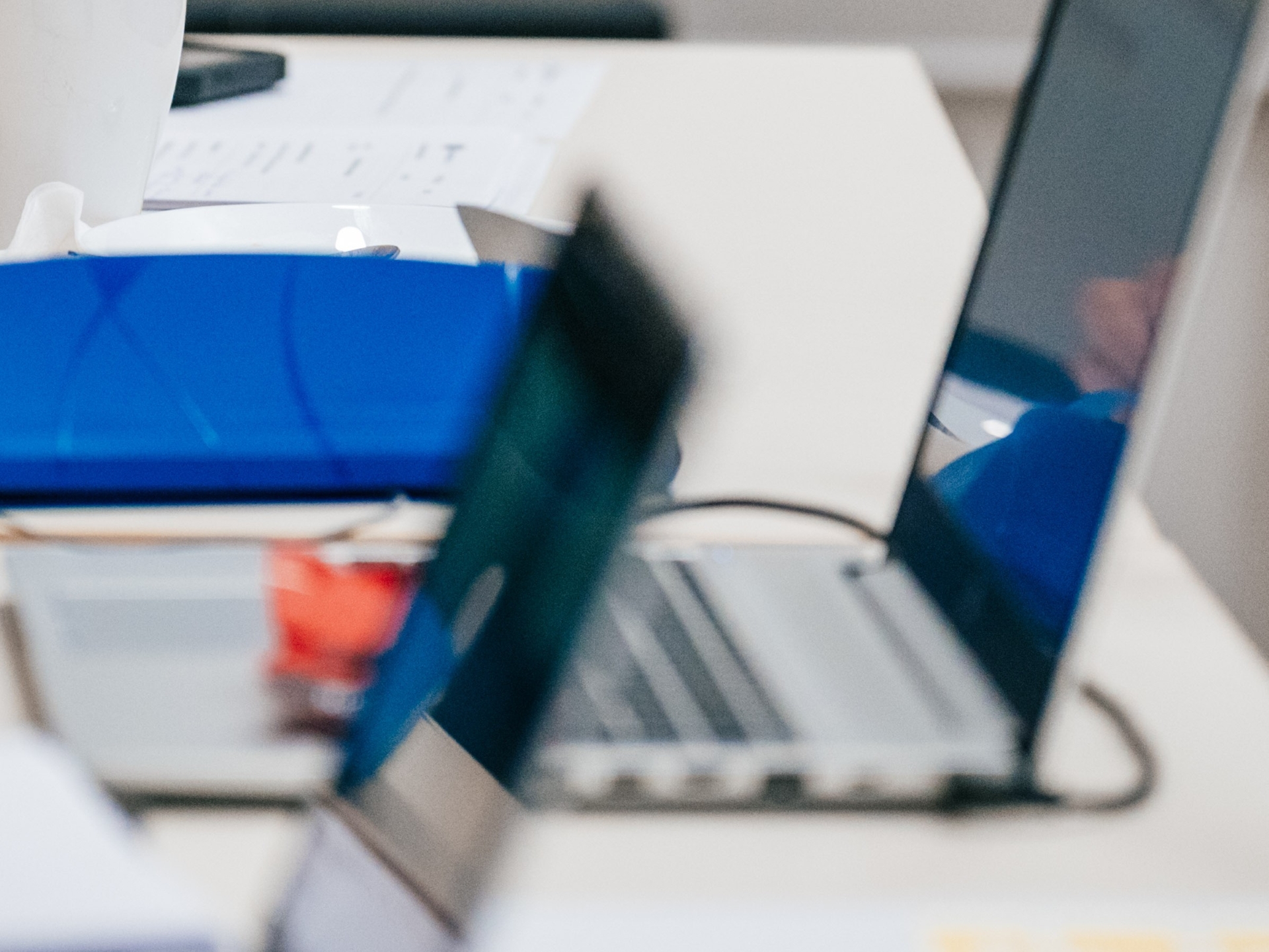 Tietokoneita ja kokouspapereita pöydällä.